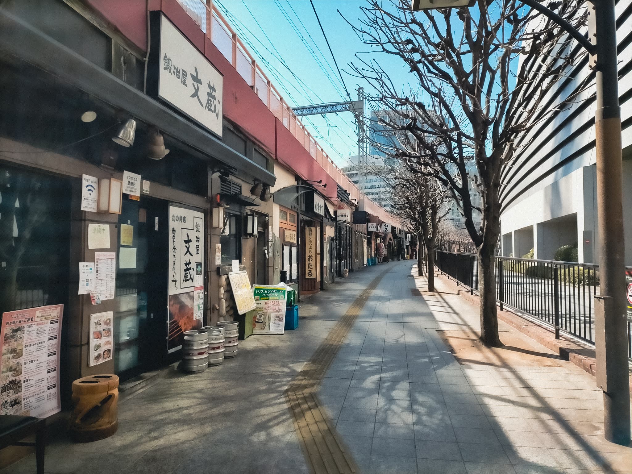 様々な飲食店の看板が並んでいる。店の上には線路があるため、全て1階建てである。