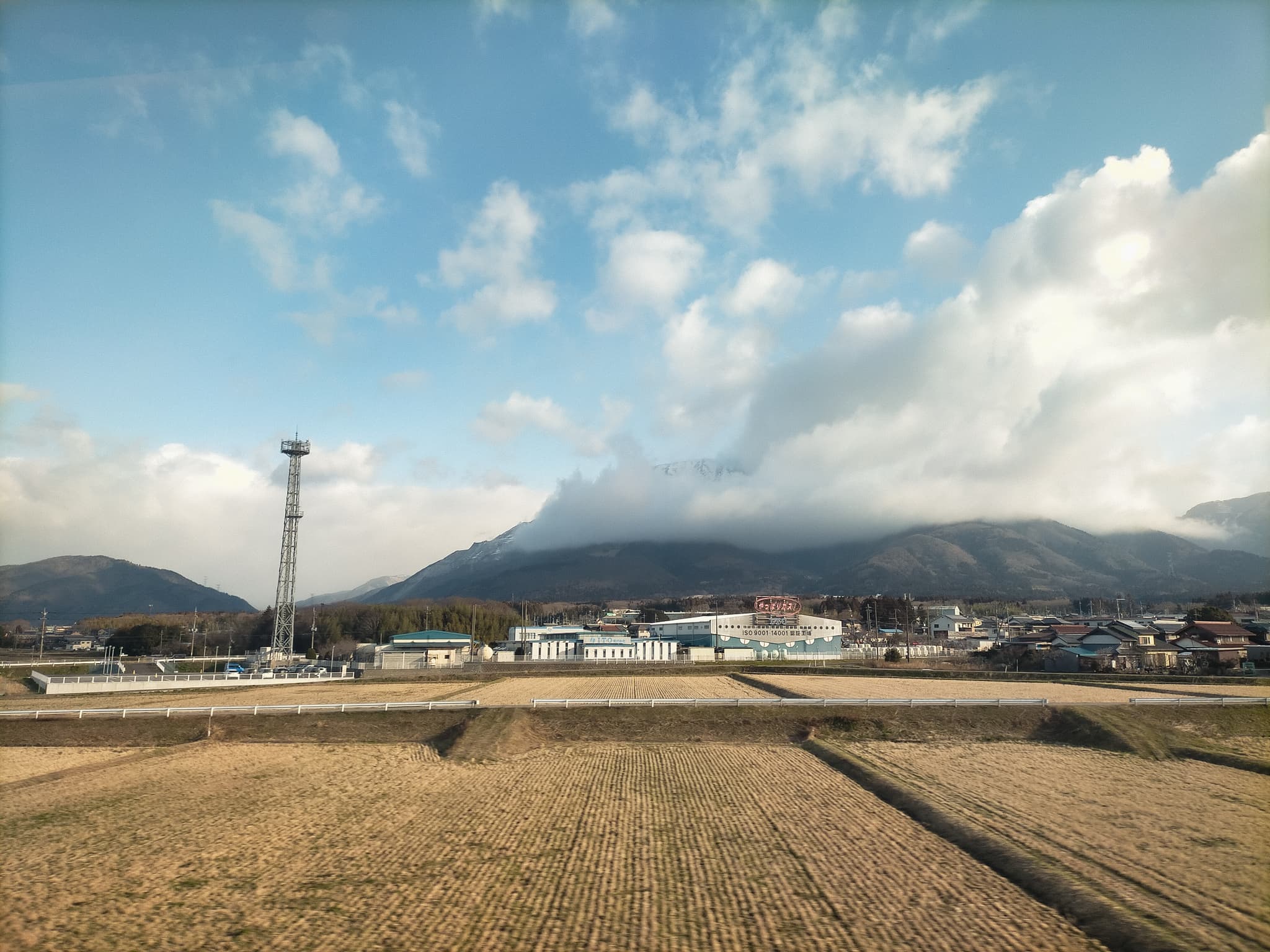 雲がかかっている伊吹山。天気は晴れで、手前には田畑が広がっている